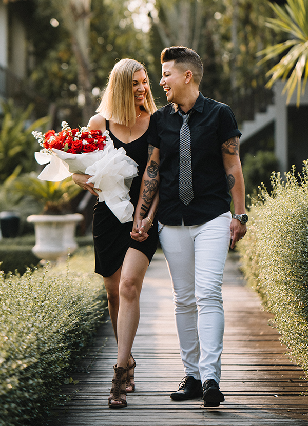 Karrie and Casey walk, holding hands, with flowers.